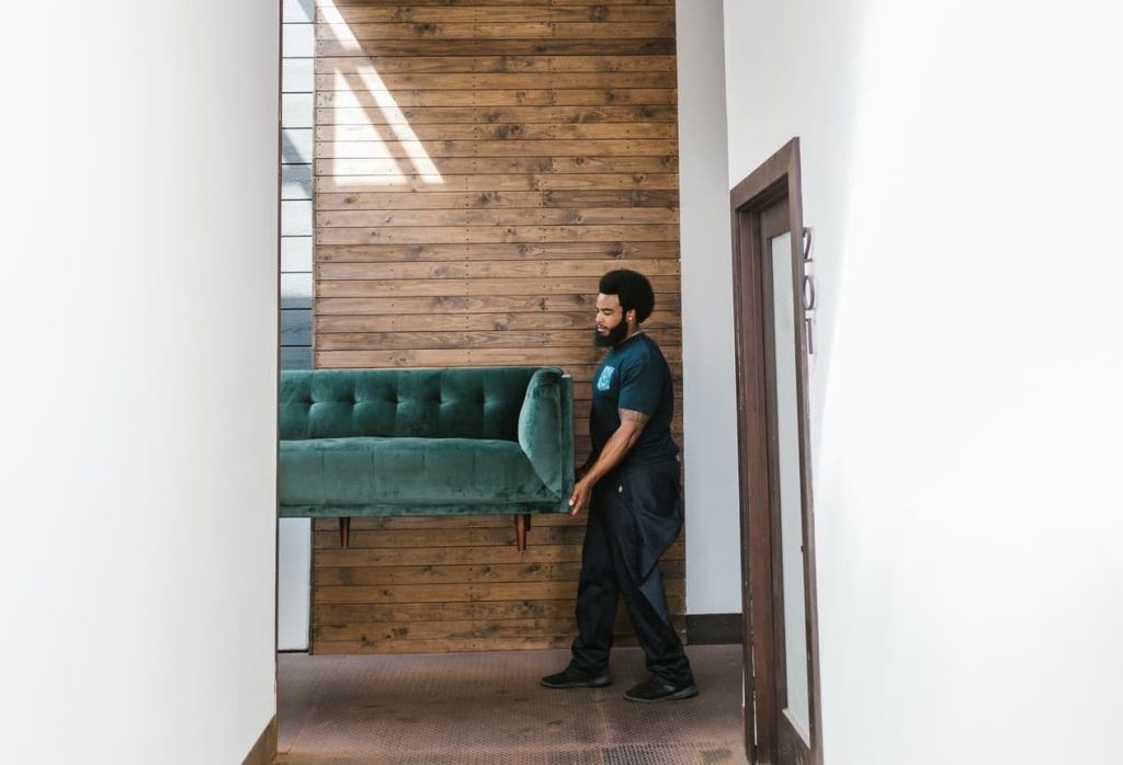 a man carrying a green sofa when moving homes